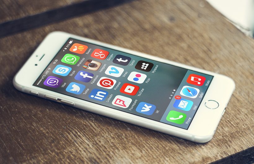 A smartphone on a table, its home screen filled with social media application icons.